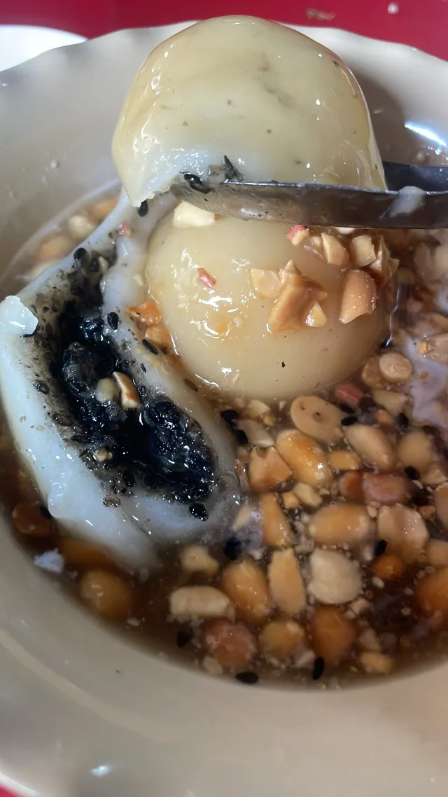 Rice balls in a sweet syrup with peanuts, sesame and a dark filling